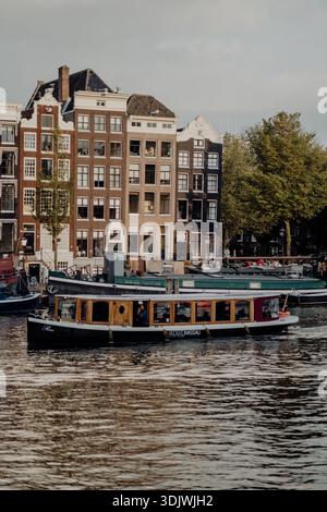 Amsterdamer Kanalhäuser und Fassaden entlang einer niederländischen gracht, klassische Architektur spiegelt sich im Wasser wider. `` Stockfoto
